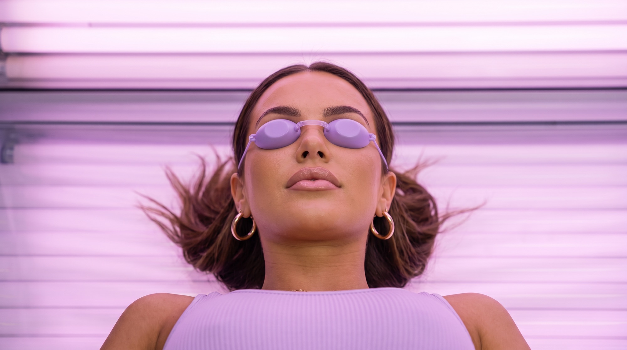 Customer wearing UV tanning goggles on a sunbed